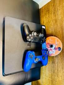 A picture of Sony PlayStation 4 slim with 2 game controllers and 1