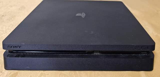 A picture of playstation 4 slim with 10 games 2 controller power cable