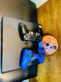 A picture of Sony PlayStation 4 slim with 2 game controllers and 1