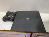 A picture of Sony PlayStation 4 pro with fifa 2022 and 2game controllers