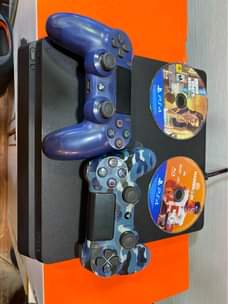 A picture of Sony PlayStation 4 slim with 2 game controllers and 2